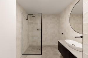 拜伦湾拜伦勋爵汽车旅馆的一间带玻璃淋浴和水槽的浴室