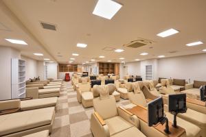 京都卢摩尔广场桑拿胶囊旅馆的一间空的讲座室,配有椅子和书桌