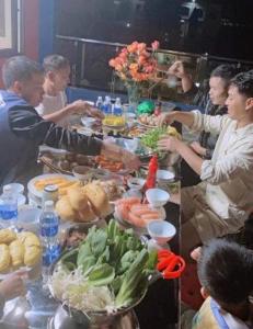 三岛县Khách Sạn Hùng Trang Hotel的一群人站在桌子旁吃着食物