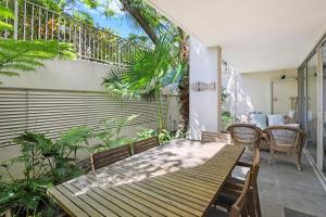 努萨角努沙港湾度假酒店的庭院配有木桌和椅子