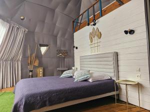 珀蒂蒂勒Domaine de l'Anse的一间卧室配有一张带紫色床单和枕头的床。