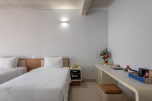 富国The Up Phu Quoc的酒店客房配有两张床和一张书桌