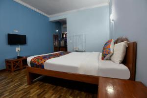 瓦加托FabHotel Prime 4D's Coast Resort的一间卧室配有一张床和一台电视