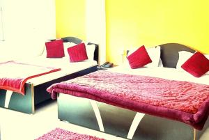 瓦拉纳西GRG Ashiyana Palace Parade Kothi Road Varanasi的客房内的两张床和红色枕头