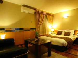 鸟栖市HOTEL Villamure ogori的酒店客房配有床、桌子和沙发。
