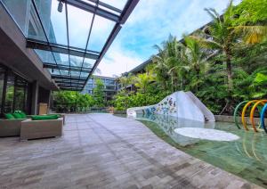 努沙杜瓦Pearl Nusa Dua Suite的一座带游泳池的建筑,设有滑梯和树木
