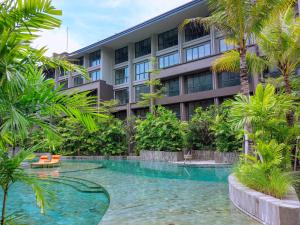 努沙杜瓦Pearl Nusa Dua Suite的大楼前设有游泳池的酒店