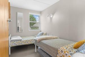 芒阿法埃Sunseeker Cottage - Mangawhai Heads Holiday Home的一间卧室配有两张床和镜子
