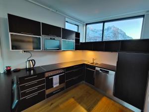 Hamn塞尼亚岛港口酒店的厨房配有黑色橱柜、水槽和2扇窗户。