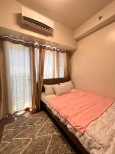 马尼拉Air Residences的一间卧室配有一张床,窗户配有空调