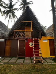 蓬蒂切里Nature Zone Resort的一座带茅草屋顶的房屋,设有楼梯和棕榈树