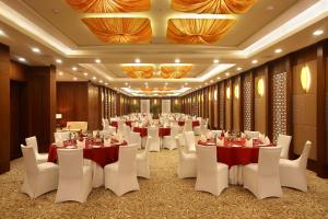 新德里新德里奥卡哈皇冠假日酒店的宴会厅配有桌子和白色椅子