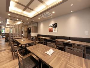 龟冈Hotel Route Inn Kyoto Kameoka的用餐室配有木桌和椅子