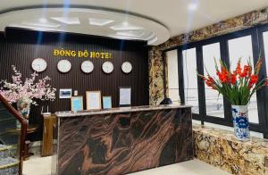 海防Đông Đô Hotel的大堂的墙上挂有时钟,鲜花盛开