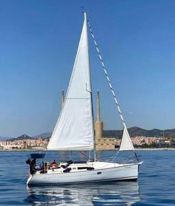 巴塞罗那Boat House Barcelona的水面上的白色帆船,以城市为背景