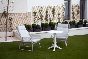 萨拉曼卡Prisma Suites的草地庭院设有两把椅子和一张桌子