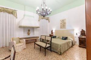 威尼斯圣安东尼酒店的一间卧室配有一张床、一把椅子和一个吊灯。
