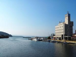 大村市大村ヤスダオーシャンホテル的一条河,船停靠在建筑物旁边