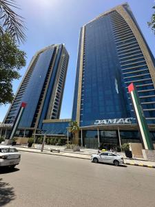 利雅德DAMAC Riyadh - Luxury Apartments的两座高楼,有汽车停在街道前
