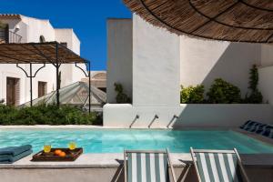 塞维利亚Casa del Rey Sabio的游泳池设有两把椅子和一张桌子,上面有橙子