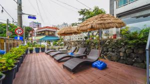 西归浦市천지연크리스탈 하버39호텔的木制甲板上配有椅子和遮阳伞的庭院