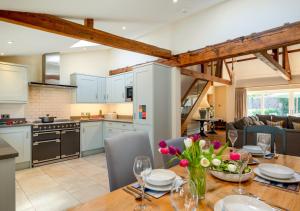 布莱克尼Boat Barn Cottage的厨房以及带花木桌的客厅。