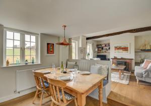 Little BarninghamAurora Cottage的厨房以及带木桌和椅子的客厅。