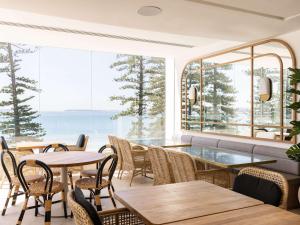 悉尼Novotel Sydney Brighton Beach的餐厅设有桌椅和大窗户。