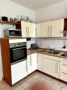 布拉格Retro Flat mit Garten, BBQ, Parken的厨房配有白色橱柜和炉灶烤箱。