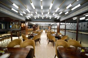 古瓦哈提Hotel Palacio的餐厅设有木桌、椅子和窗户。