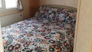 斯凯格内斯3-Bed 8 berth static caravan in ingoldmells的卧室内的一张带花卉棉被的床