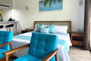 康隆尼角Residence Le Point Choisy的一间卧室配有一张床和两张蓝色椅子