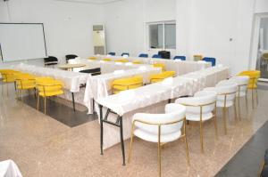 波多诺伏Freedom Palace Hôtel的一间会议室,配有白色的桌子和黄色的椅子