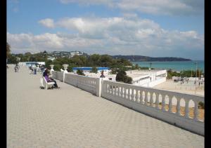 拉马萨The Arabesque House的坐在海滩上桥上的长椅上的女人
