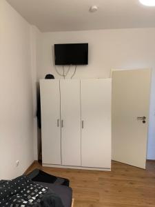 盖尔森基兴Domum 2 Moderne Ferien- Monteurapartments inkl Wlan und Waschmaschine in Gelsenkirchen的卧室配有白色橱柜和平面电视。