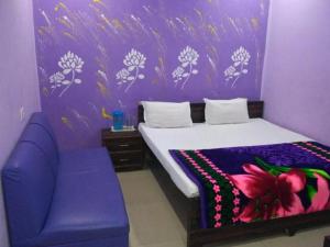 坎普尔Hotel Atithi Galaxy Kanpur Near Railway Station Kanpur - Wonderfull Stay with Family的紫色卧室配有一张床和一张紫色沙发