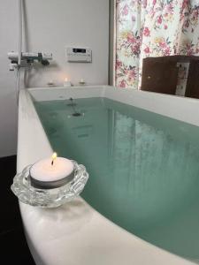 富山Platina Luxe House的浴缸里的玻璃桌上的蜡烛