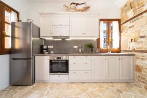 迈伊斯蒂Alexandros的厨房配有白色橱柜和不锈钢冰箱