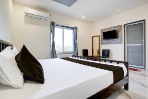 巴罗达OYO Hotel Ambika的卧室设有一张白色大床和一扇窗户。
