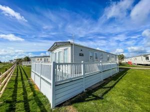 洛斯托夫特Beautiful 6 Berth Caravan With Full Sea Views For Hire In Suffolk Ref 68002cr的草场上带栅栏的白色房子