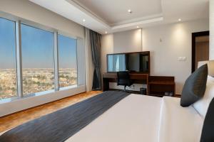 利雅德Celin Home Alsahafa - Riyadh City View的一间卧室配有一张床和一张书桌及电视