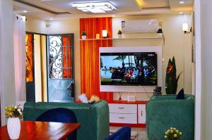 雅温得Le meublé des voyageurs的客厅配有平面电视和绿色椅子。