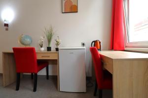 维也纳Golden’s Apart-Hotel的厨房配有书桌、冰箱和红色椅子