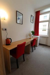 维也纳Golden’s Apart-Hotel的配有书桌和2把红色椅子的房间