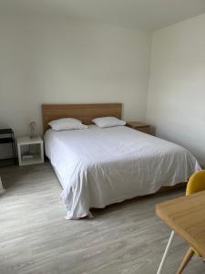 维勒班特Cosy 2 pièces et parking 30 mns Gare du Nord by immokitbnb的卧室配有白色的床和木桌