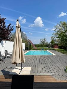 费尔特德Freistehendes Ferienhaus mit Swimmingpool, Kamin, Internet, unweit Neusiedlersee的游泳池旁甲板上的遮阳伞