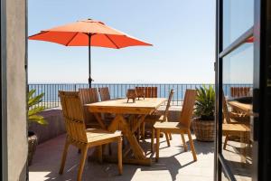 布伦德Belle villa vue mer- Erbalunga à 2 pas de la plage的庭院里配有一张木桌和椅子及遮阳伞