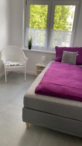 桑德Villa Mariensiel 1OG li的一间卧室配有一张紫色的床和一把椅子