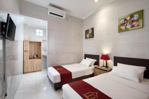 库塔Angkul Angkul Beach Inn Kuta by Kamara的酒店客房设有两张床和电视。