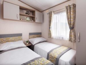 坎伯利SBL38 Caravan at Camber Sands - quiet location的客房设有两张床和窗户。